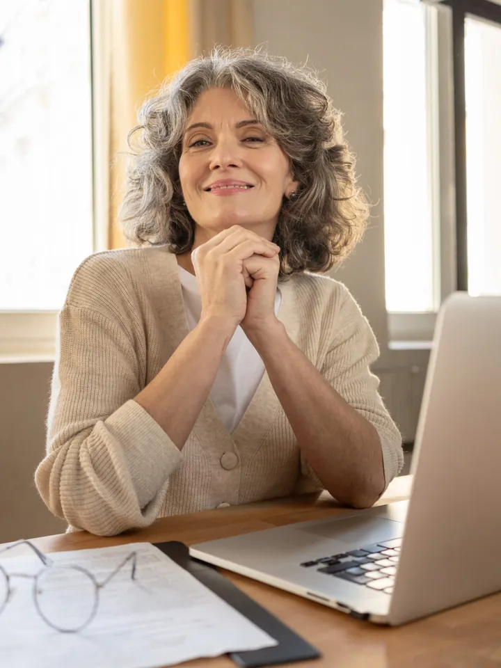 Senhora sorridente diante de um computador
